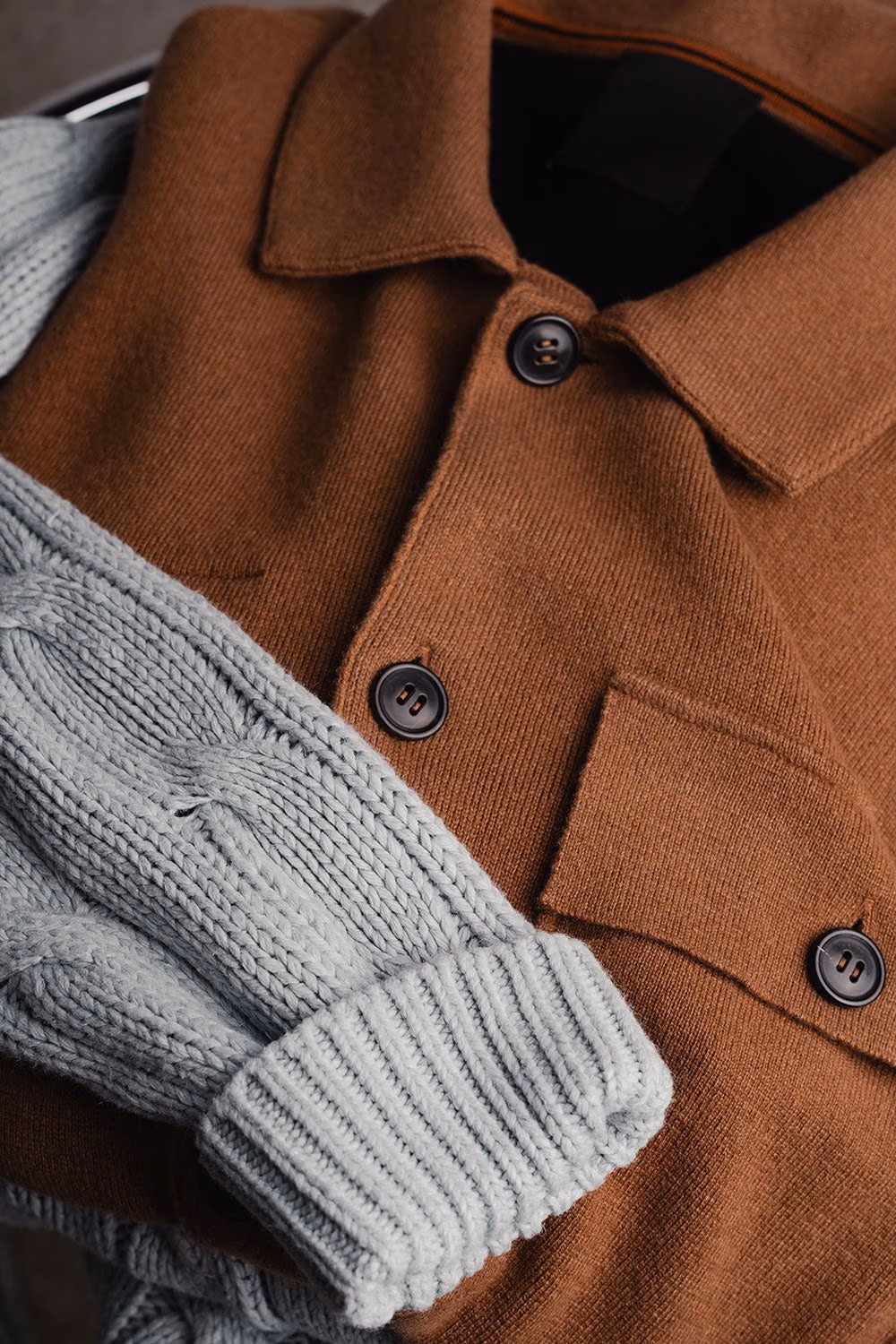 Grey cable-knit sweater under a brown suede jacket