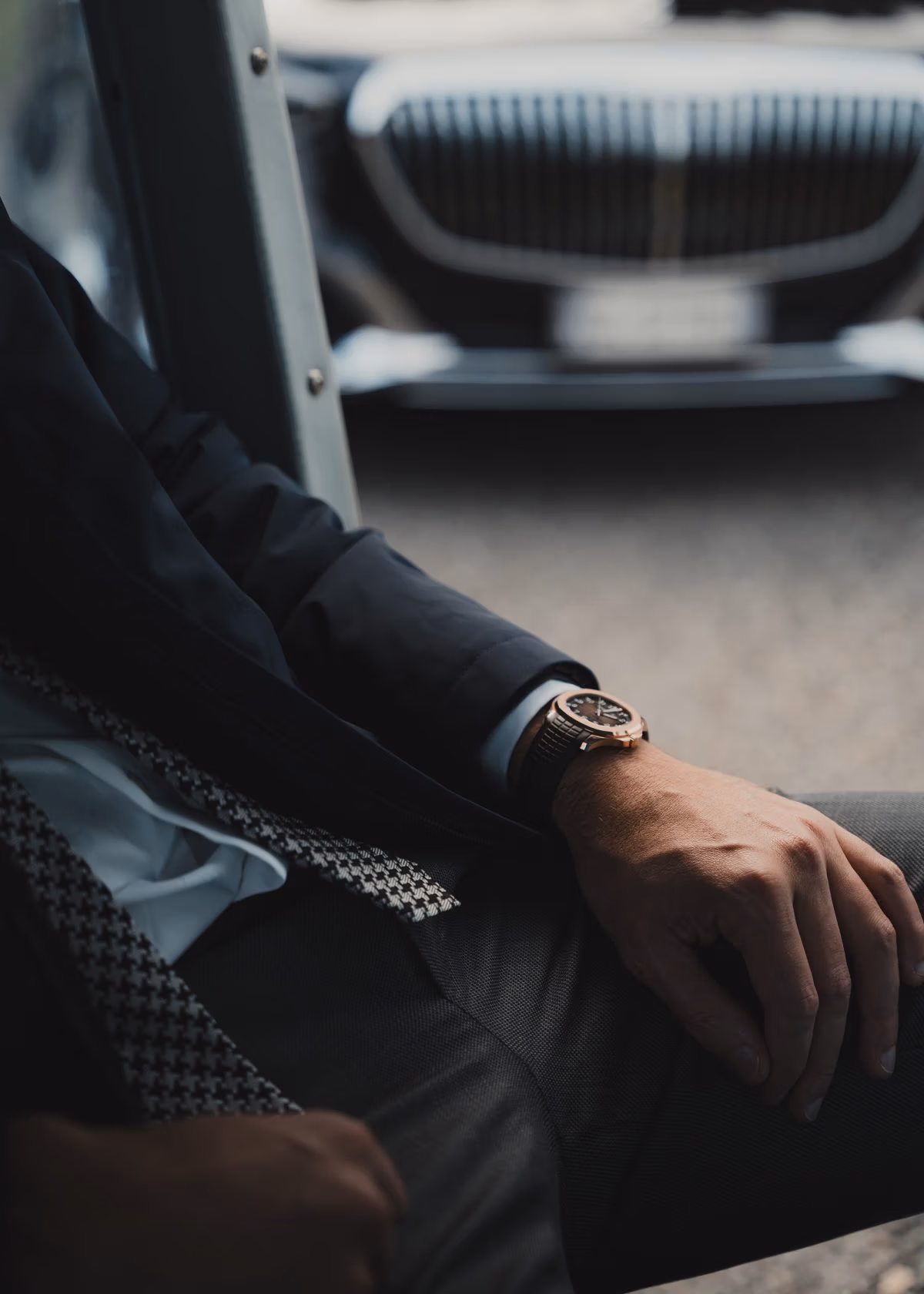 Man in a tailored suit wearing a wristwatch, seated in a car